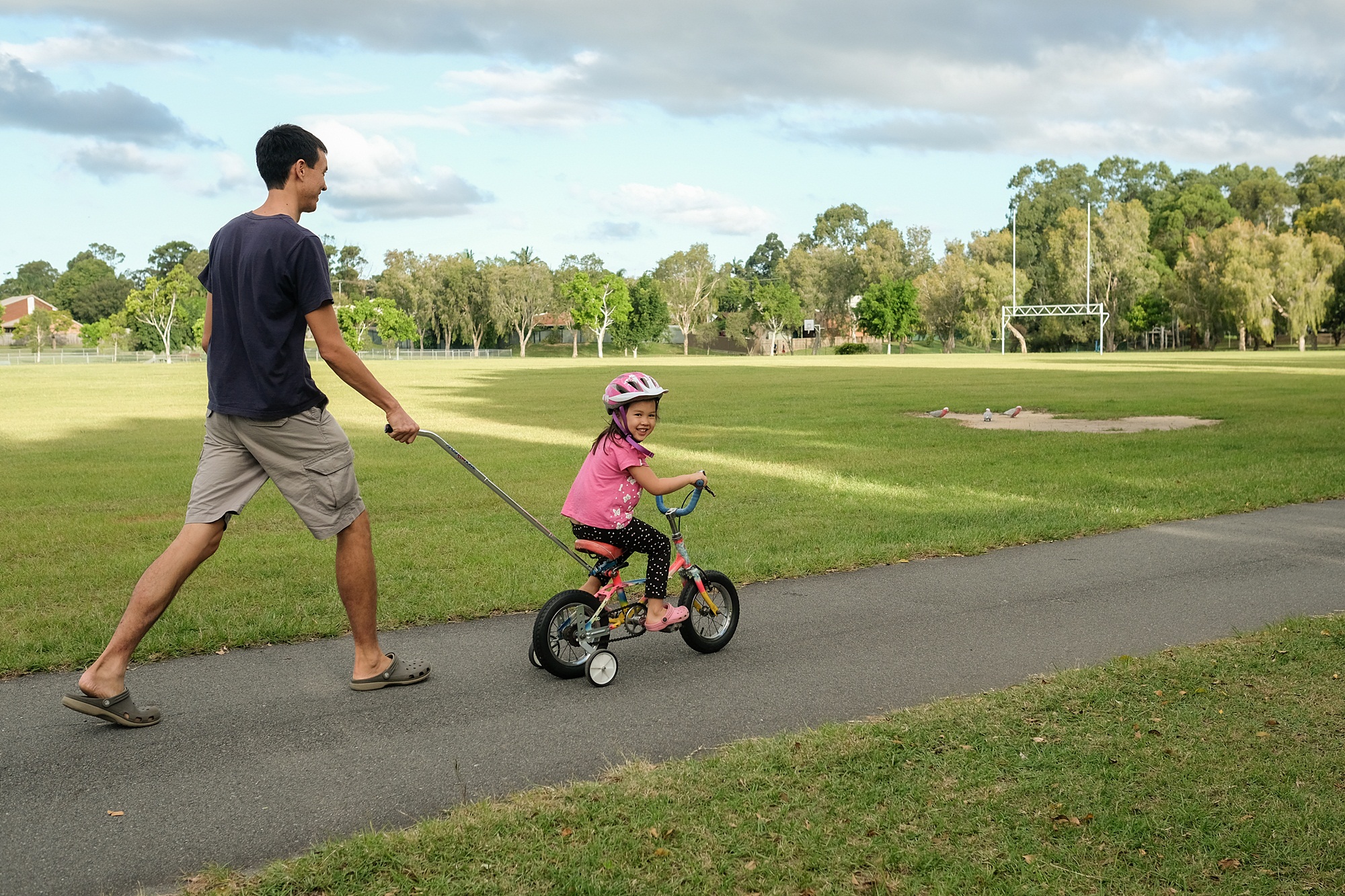 A parent helping a child enjoy a bike ride