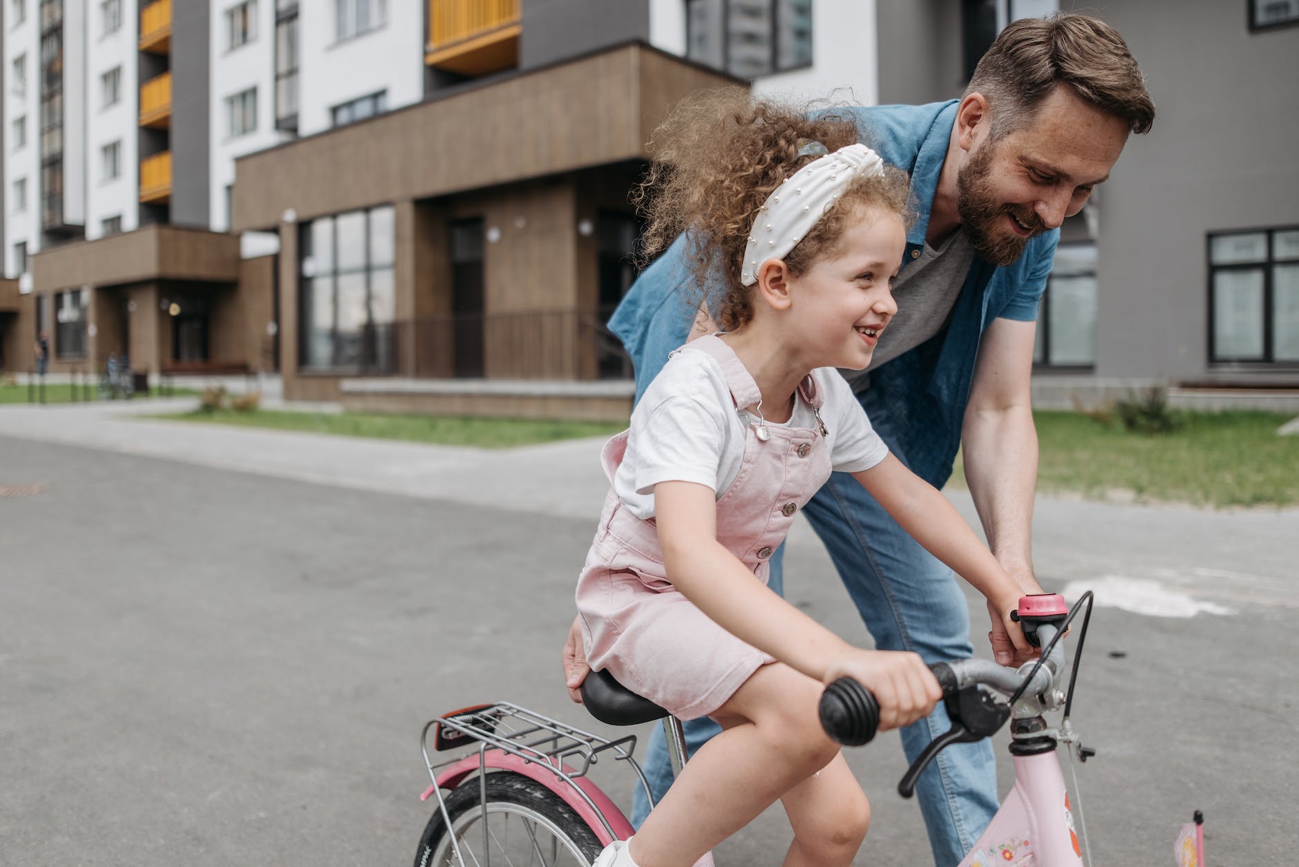 girl learning how to ride a bicycle with her dad