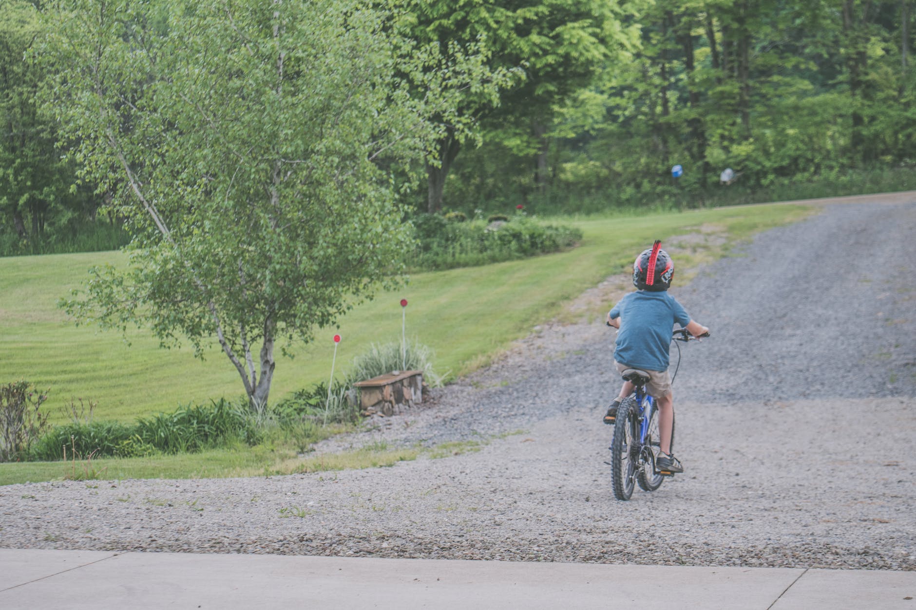 boy wearing blue t shirt and beige shorts outfit riding on black bicycle at daytime
