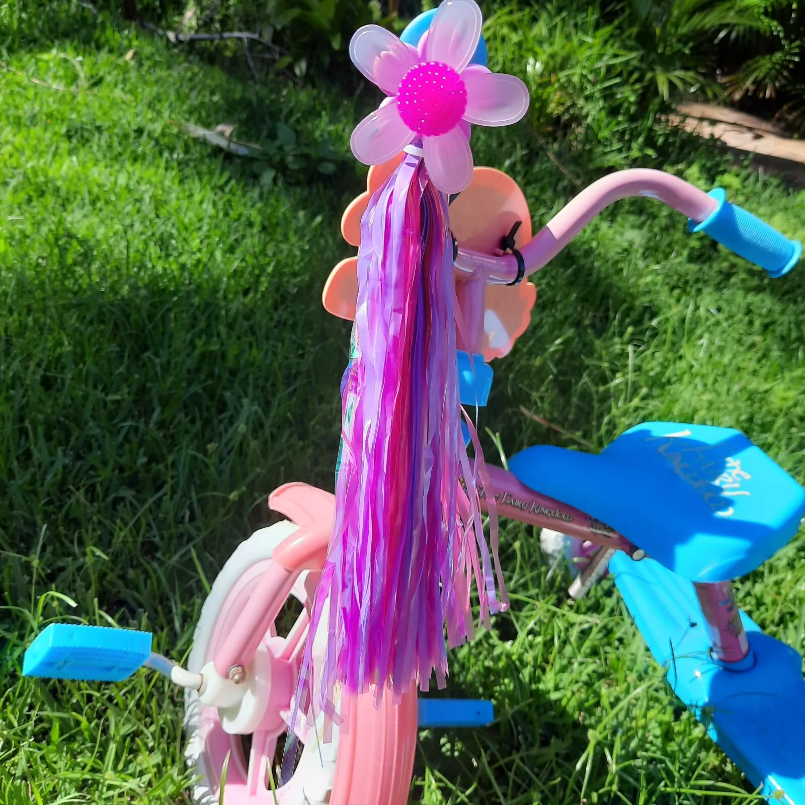 Neon purple, pink, and silver windmill bike streamers on kids’ bicycle